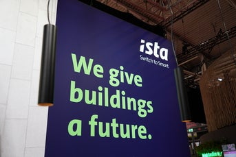 Großes Banner mit dem ista-Logo und dem Slogan „We give buildings a future.“ auf einer Messewand, umgeben von modernem Messedesign und Beleuchtung.