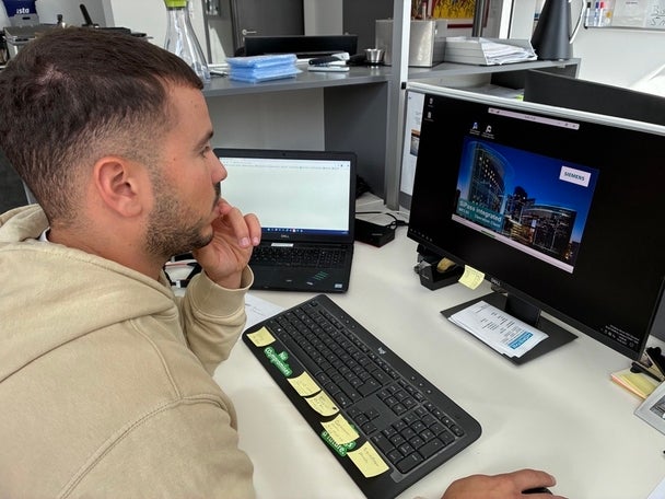 Ein Mann sitzt konzentriert am Schreibtisch vor zwei Monitoren und arbeitet am Computer.