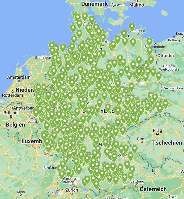 Auf dem Bild ist eine Karte von Deutschland und Teilen der angrenzenden Länder zu sehen, auf der viele Standorte mit grünen Markierungspunkten hervorgehoben sind. Die Dichte der Markierungen zeigt die Standorte zeigt, wie viele Schulen sich bereits an den KlimaPaketen beteiligen.