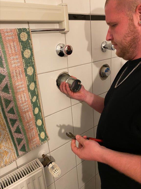 Kundendiensttechniker prüft Warmwasserzähler im Badezimmer.