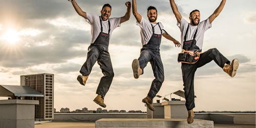 Drei Männer in Arbeitsbekleidung springen auf einem Dach in die Luft: Symbolbild für ista Service Partner