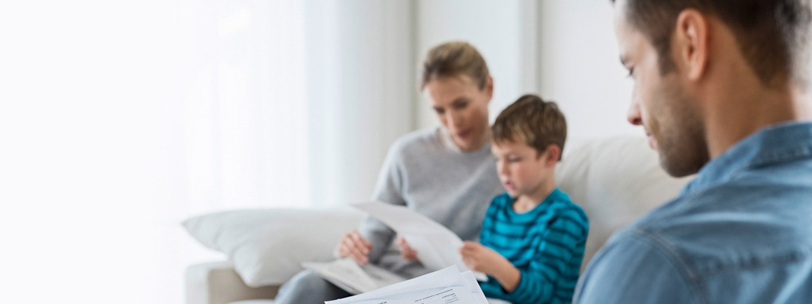 Eine Familie, Mutter, Vater, Kind, sitzt auf der Couch und schaut auf eine Abrechnung der ista. 